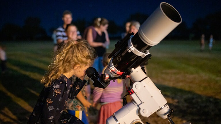 School girl looking through telescope