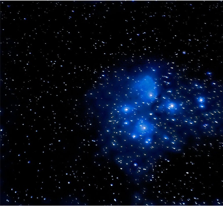 the hot blue stars of the Pleiades open cluster glow against dark space
