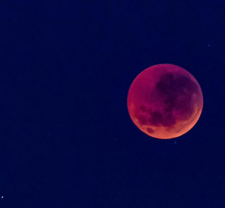 A lunar eclipse, as the Moon passes through Earth's shadow, the refracted light hitting the surface of the Moon gives it a red glow.