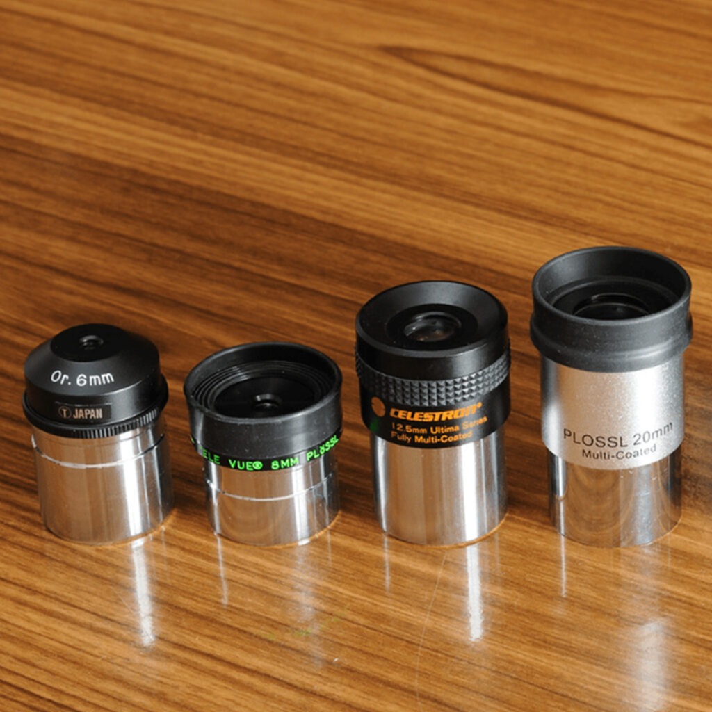 telescope eyepieces lined up on a desk. Starting low is one of our top tips.