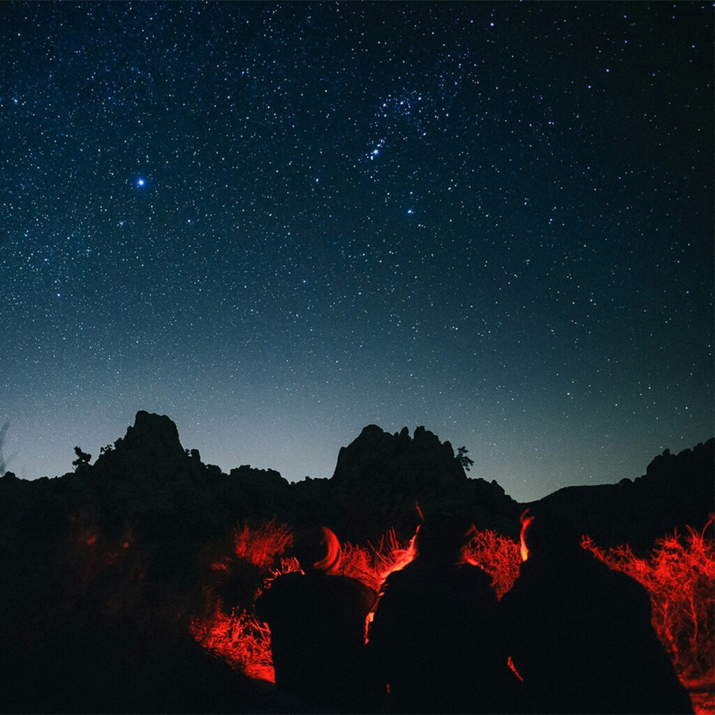 Friends sit in the dark illuminated only by a red light. Getting comfortable with the dark is one of our top tips.