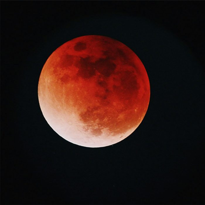 A full moon in eclipse, with a red colour against a black background. Photo by